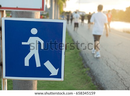Closeup walk or jogging trail in the park signpost  with blurred people background.