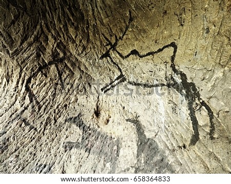 Caveman symbols on sandstone wall. Paint of human hunting,  prehistoric picture.. Black carbon paint of deer on sandstone wall, prehistorical picture. Abstract art in cave.  Discovery of history