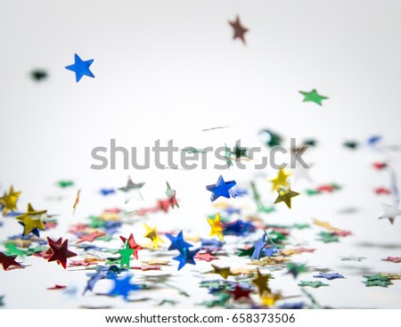 Falling stars
A high key image of colourful shiny star confetti falling to the ground