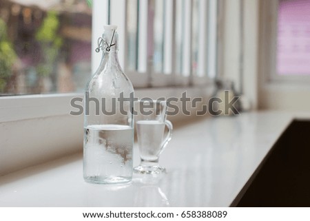 Glass of water with a bottle on table. Shallow depth of field. Horizontal photo