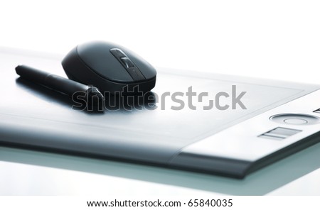 A close-up of a pen and mouse on a digital tablet