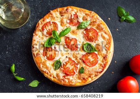 Pizza Margherita on black stone background. Homemade Pizza Margarita with Tomatoes, Basil and Mozzarella Cheese. Royalty-Free Stock Photo #658408219