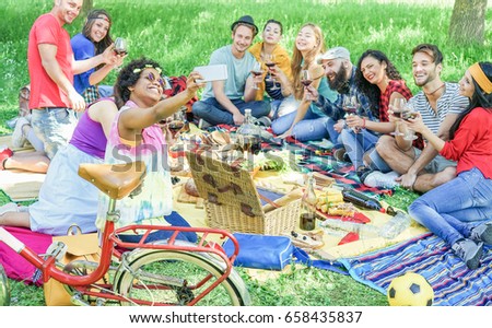 Happy diverse culture friends taking selfie portrait at picnic party outdoor - Young people drinking wine,eating and having fun together - Friendship concept - Focus on afro girl face - Warm filter