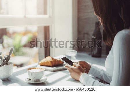 Close-up image of young hipster girl sitting at cozy cafe and using modern smart phone, Female hands typing text message via cellphone