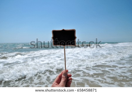 Wooden black plank in hand against the sea