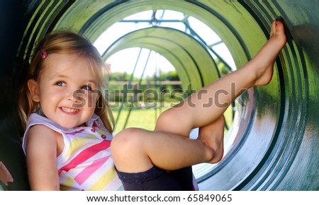 Cute girl poses in tunnel at the playground