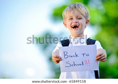 Young boy holds up handwritten sign "Back to school!"