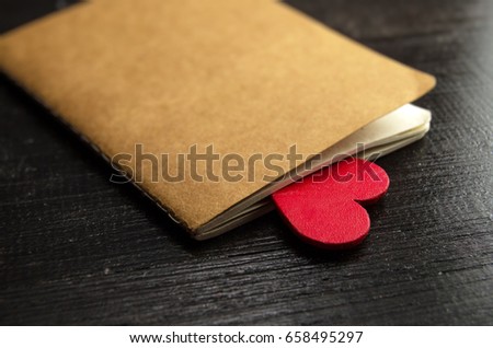 The craft notebook with a love letter and a beautiful heart on wooden background