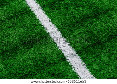 A sports ground with an artificial green lawn and white markings. Selective focus