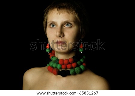 Young woman with bare shoulders in her wearing a necklace and earrings made of wool. Ethnos