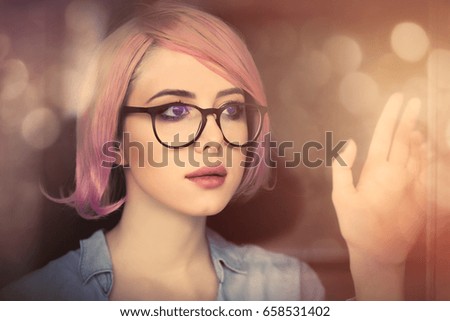 beautiful young woman looking at the window and touching it. Portrait with bokeh on background