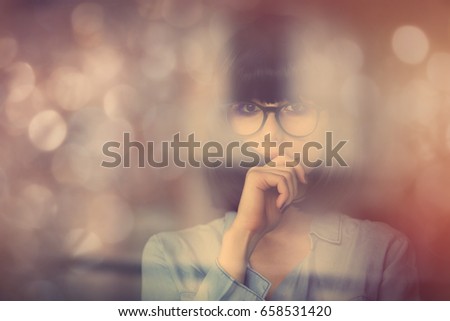 beautiful young woman standing near the window and touching her hair. Portrait with bokeh on background
