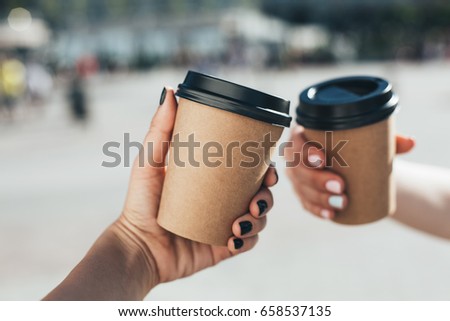 Two paper coffee cups in women's hands with perfect manicure. Royalty-Free Stock Photo #658537135