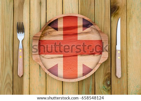 Concept of English cuisine. Wooden plate with a England flag, fork and knife on a wooden background