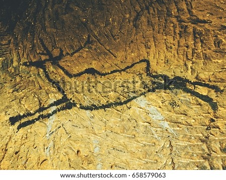 Caveman symbols on sandstone wall. Paint of human hunting,  prehistoric picture.. Black carbon paint of deer on sandstone wall, prehistorical picture. Abstract art in sandstone cave.  Human history