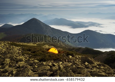 Panorama of the night mountains from the peak of Synyak in the Gorgan Mountains above Bukovel resort. The sea of fog in the valley against the background of high peaks in the moonlight