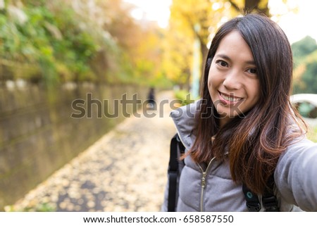 Woman taking selife with autumn Ginkgo tree