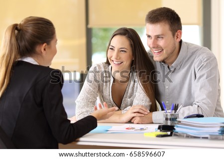 Happy couple talking with a real estate agent at office Royalty-Free Stock Photo #658596607
