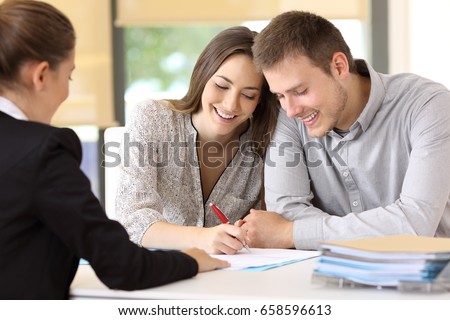 Happy couple signing a contract together at office