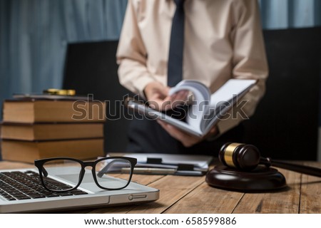 Business lawyer working hard at office desk workplace with book and documents.
