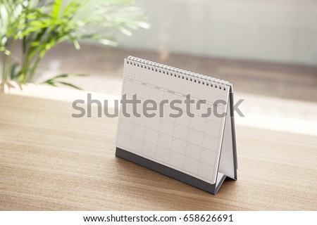 A desk calendar on the wood desk(table)