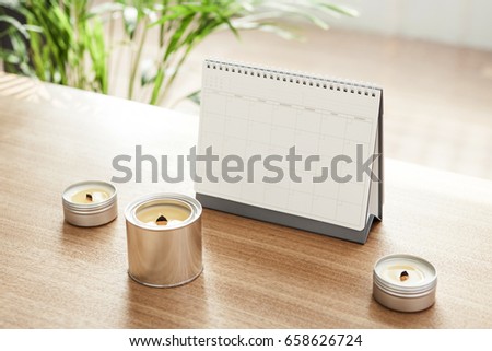 A calendar and candle on the wood desk(table)