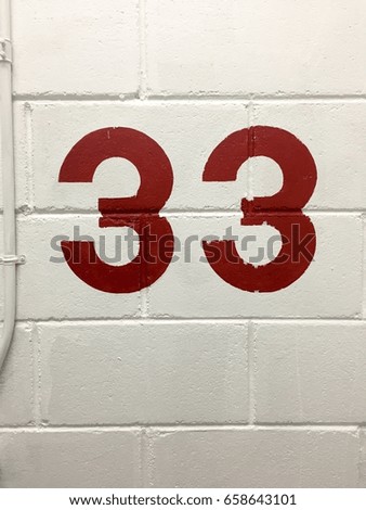 Red 33 floors level signs on the white cement brick wall
