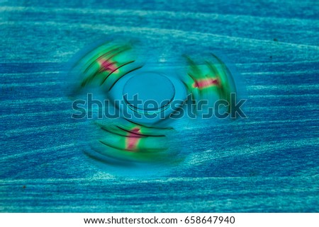 Fidget Spinner in fluorescent UV glowing isolated background for stress release during work
