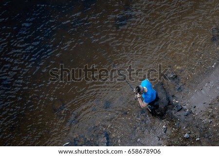 A fisherman with a smartphone catches fish. Top view.