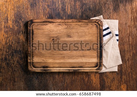 Old Cutting Board with cloth napkin on a old wooden table, top view Royalty-Free Stock Photo #658687498