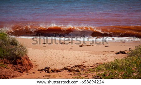 Red waves breaking on beach at high tide at James Price Point, Kimberley, Western Australia Royalty-Free Stock Photo #658694224