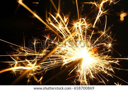 Sparkler background / A sparkler is a type of hand-held firework that burns slowly while emitting colored flames, sparks, and other effect