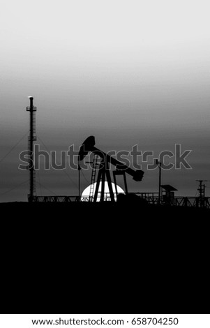 Silhouette of crude oil pump in oilfield at sunset - Black and white 
 