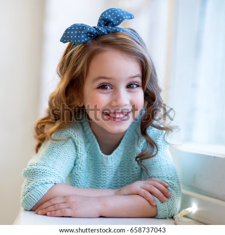 sly girl with accessories in her hair blue blouse and jeans smiling. fashion Royalty-Free Stock Photo #658737043