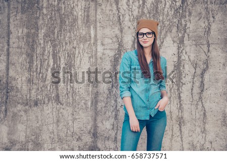 Street fashion, style, youth, swag, denim concept. Female modelm is in fashionable jeans outfit, posing on the concrete wall`s background outside Royalty-Free Stock Photo #658737571