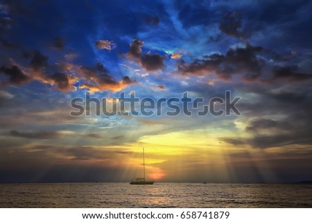 seascape scenic sunset and anchored boat with deflated sails off the coast of Thailand