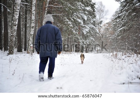 Old man hunter walking with his dog alone in winter forest