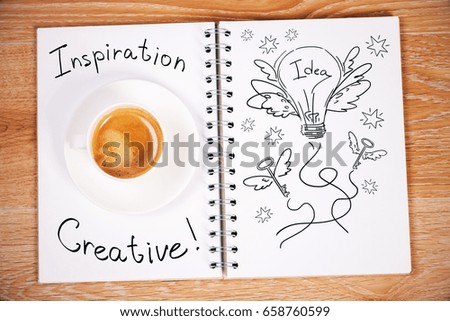 Top view of wooden table with lamp sketch in open spiral notepad and coffee cup. Inspiration concept