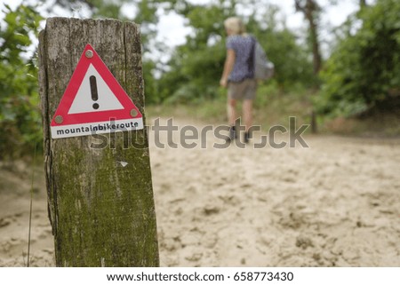 Warning sign in the forest for hikers crossing a mountain bike route