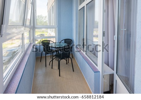 A table and three chairs on the balcony in the apartment of a multistory apartment building Royalty-Free Stock Photo #658812184