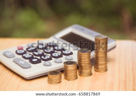 Growing coins and calculator on wood with green tree bokeh background vintage tone. Financial growth, saving money, business finance wealth and success concept.