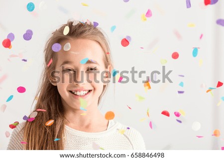 Cute little girl smiling with confetti falling down