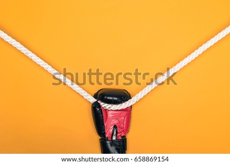 Closeup view of boxing glove hanging on rope isolated on yellow