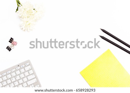 yellow Notepad, computer keyboard, paper clips, two black pencil and a chrysanthemum flower on a white background. Minimal business concept of working place in the offices. Flat lay. Top view.