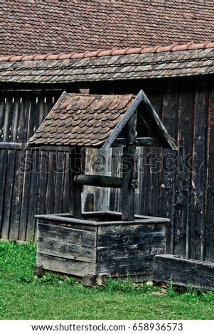 Old water well with pulley. Wooden water well in european village, Transylvania