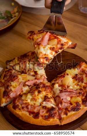 Hawaiian Pizza with Pineapple, Ham Slice, Bacon Slice, Mozzarella Cheese, Pizza Sauce on wooden plate.