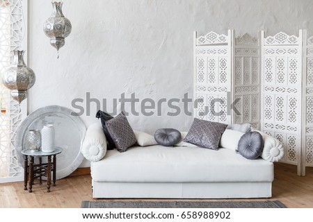 Eastern traditional interior. Morocco style room. Arch and window with beautiful carving. White and gray room with beautiful white sofa and pillows Royalty-Free Stock Photo #658988902