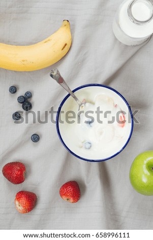 Top view of yogurt and fresh fruit on gray tablecloth background.