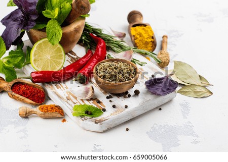 Selection of herbs, spices and wooden cutting board on white stone table. Copy space