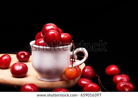 The cherry in the white cup sprinkles on the black background